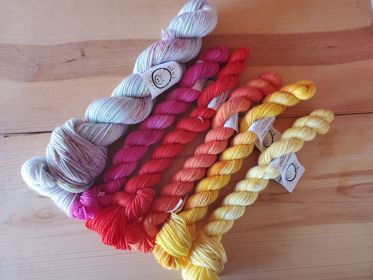 One large skein and five smaller ones rest on a wooden background.