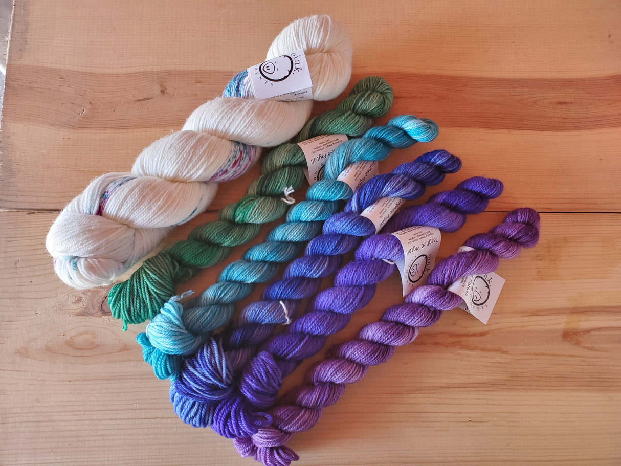 One large skein and five smaller ones rest on a wooden background.