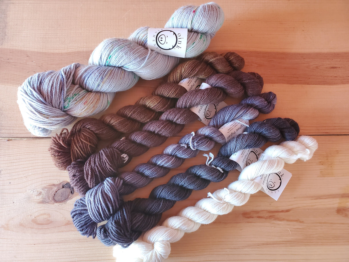 One large skein and five smaller ones rest on a wooden background.