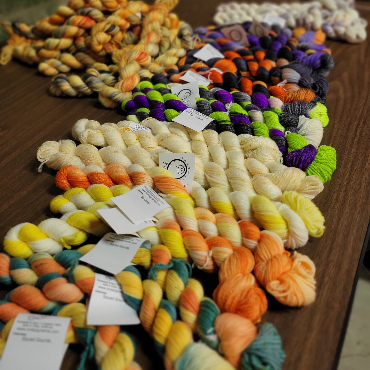 A riot of mini skeins rest on a dark wooden background.