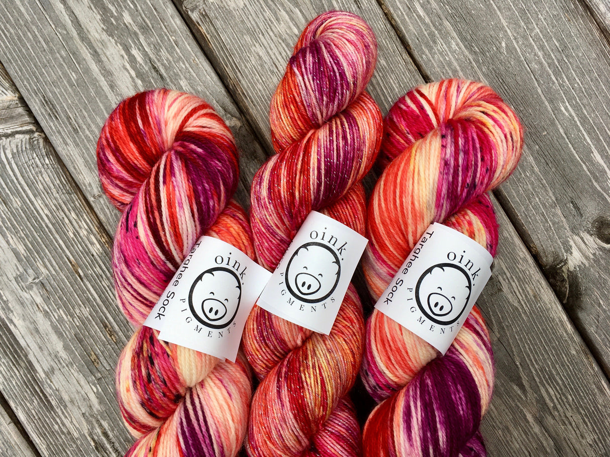 Three skeins of yarn rest on a light wooden background.