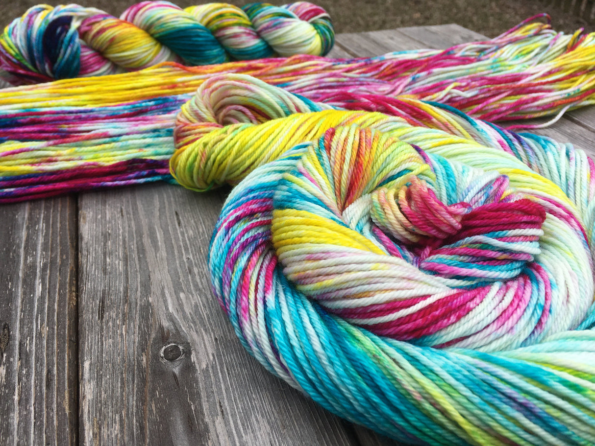 Three skeins of yarn in various stages of being skeined up rest on a wooden background.