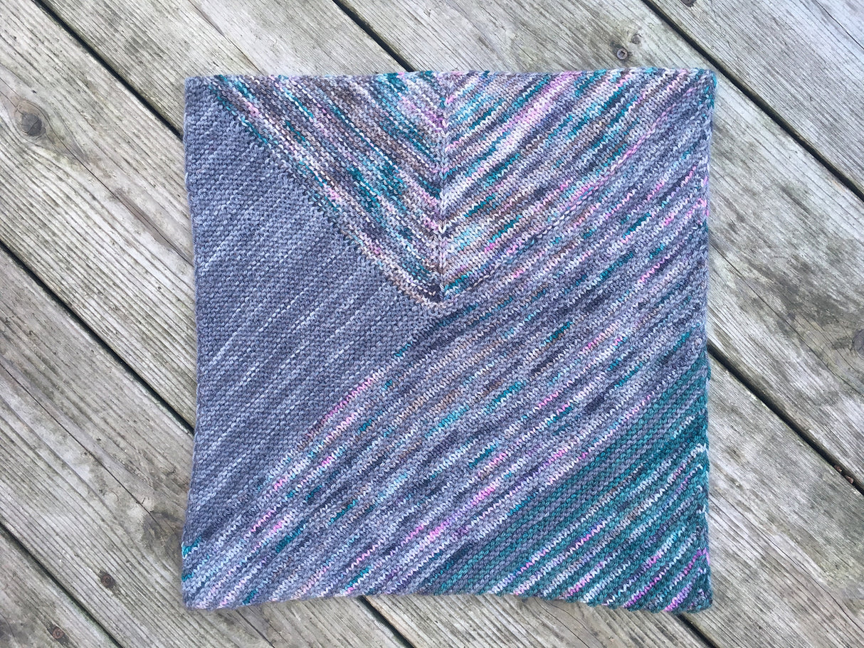 A view of a cowl made of modular shapes resting on a wooden background.