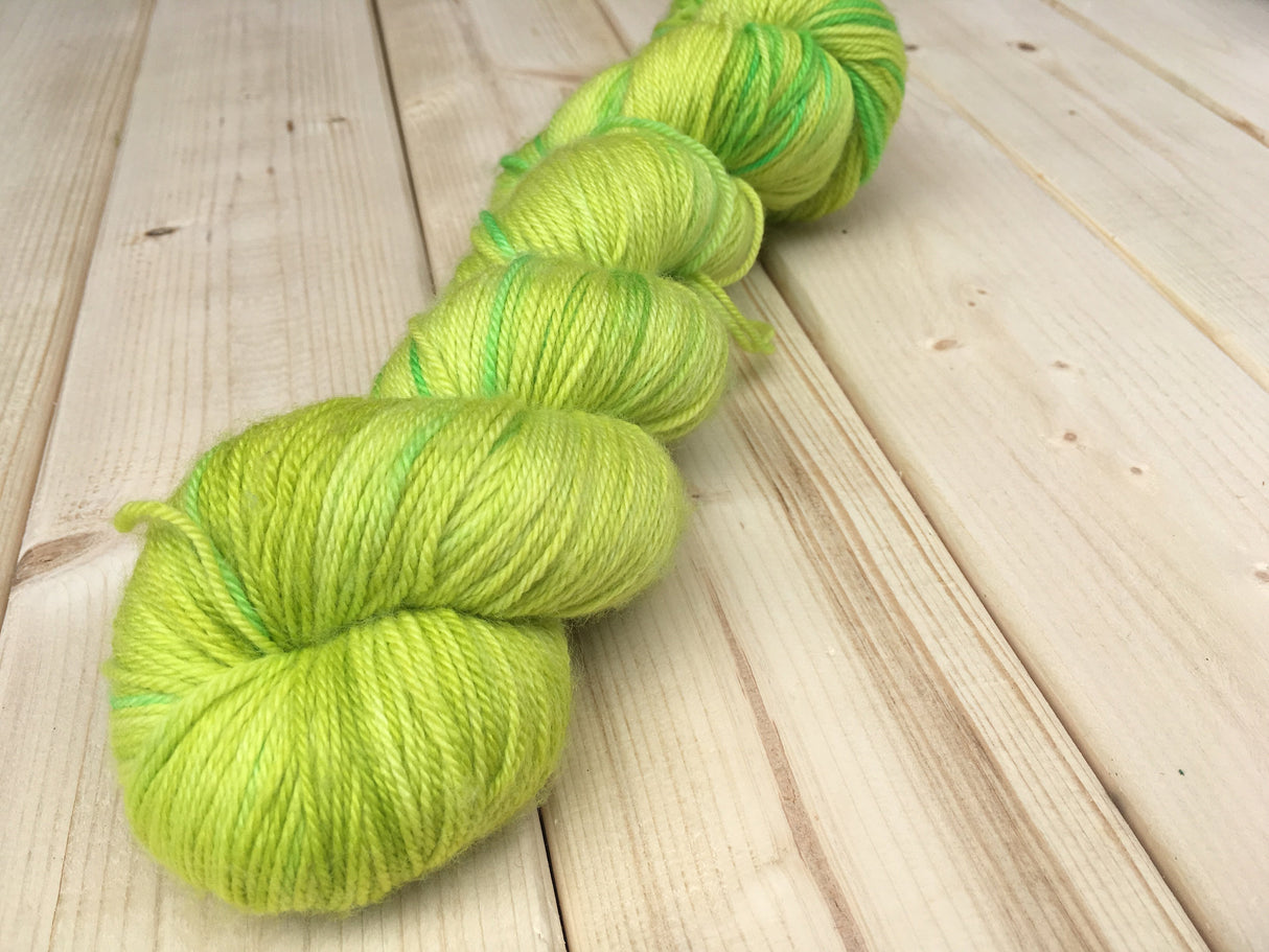a bright and vivid skein of yarn rests on a wooden background.