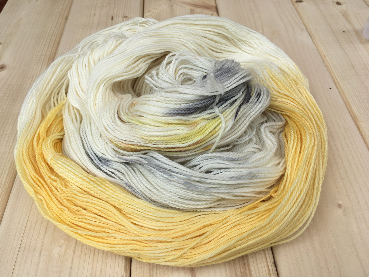 An untwisted skein rests in a lush pile atop a light wooden background.