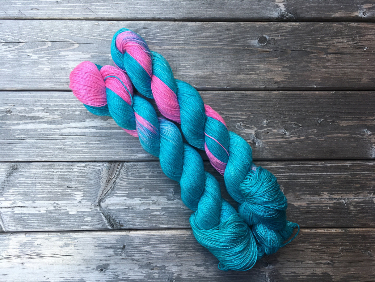 two brightly colored skeins rest against a dark wooden background.