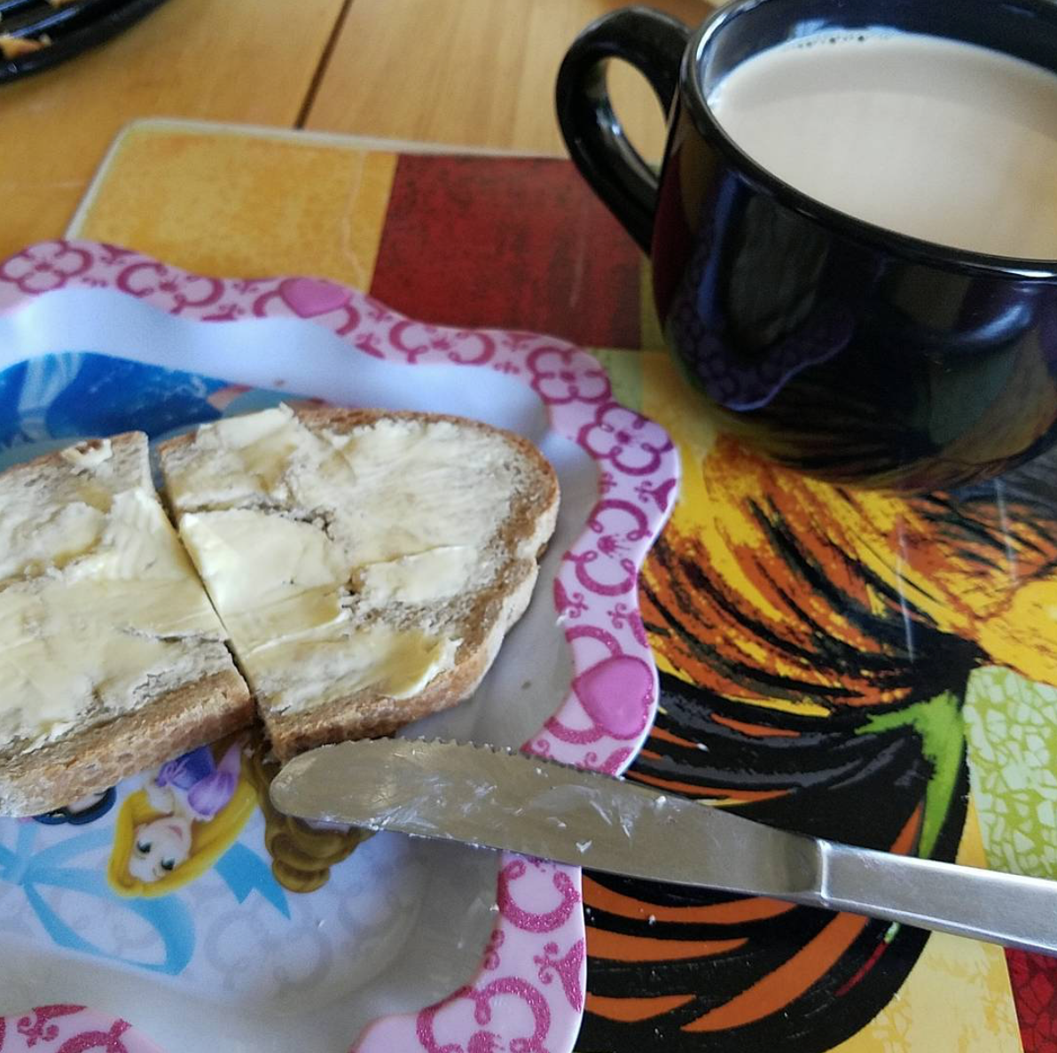 Scrumptious looking toast with plenty of schmear waits on a Disney Princess plate. A dark mug of warm beverage rests in the upper right corner.