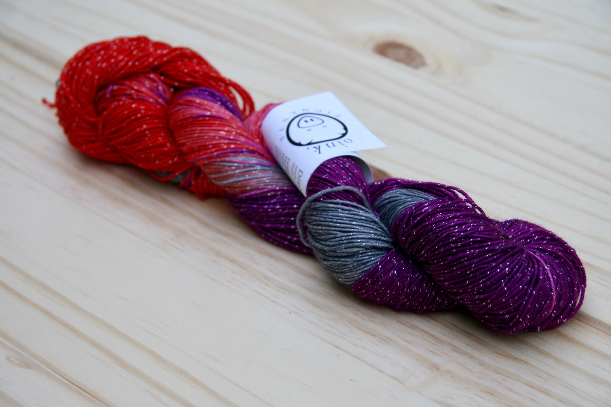 A single twist of yarn rests on a wooden background.