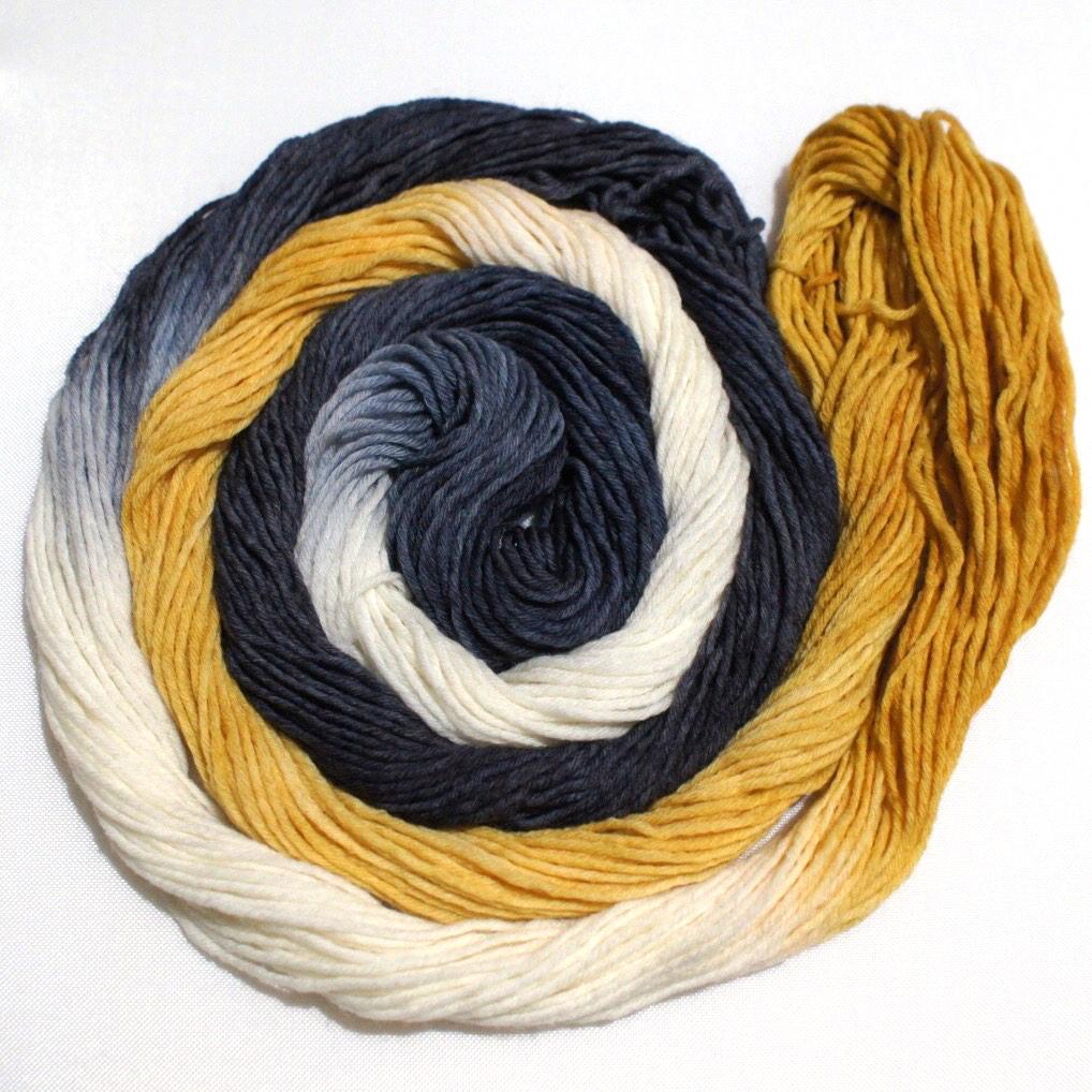 A swirling round of richly colored yarn rests against a clean white background.
