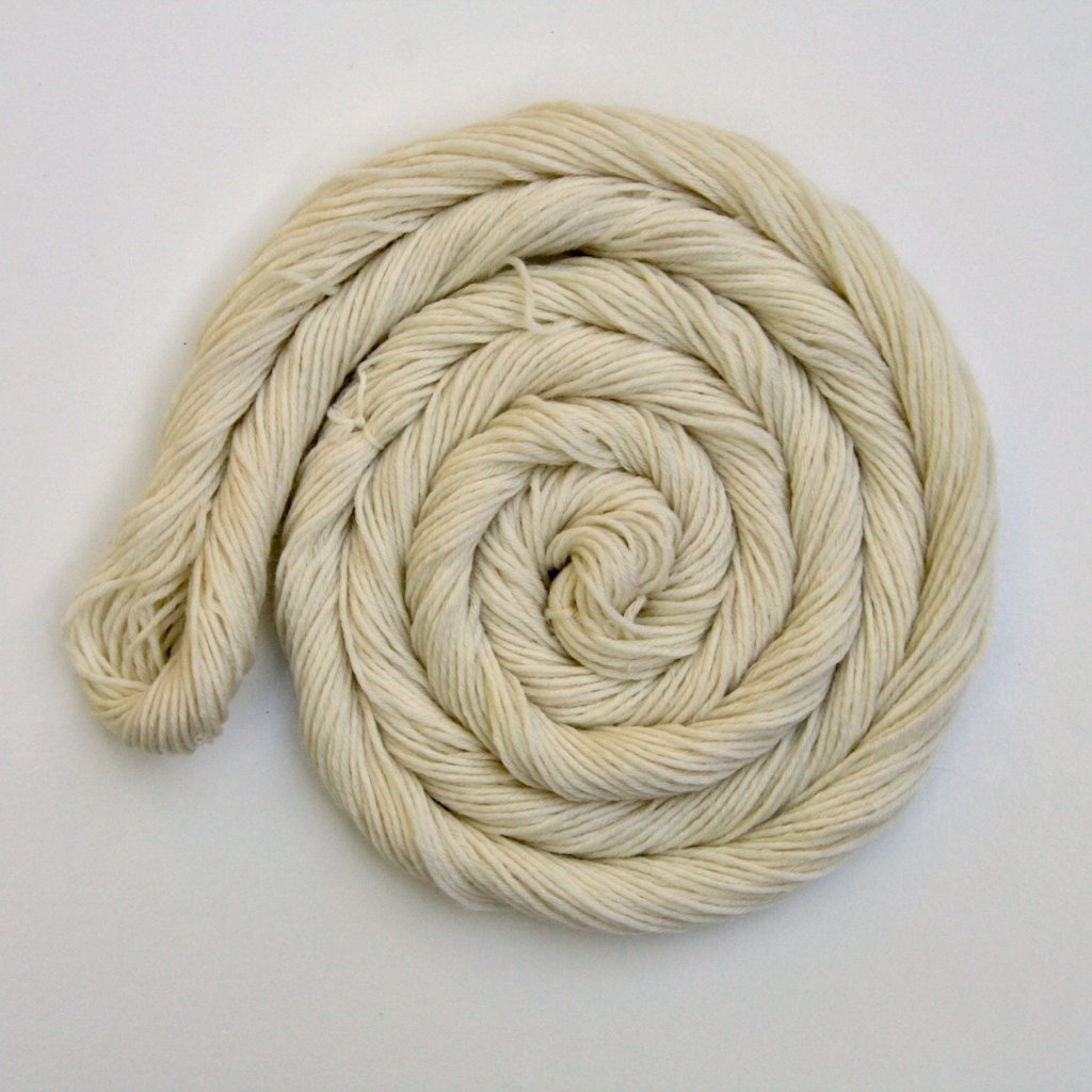 A swirl of pale cream yarn rests on a clean white background.