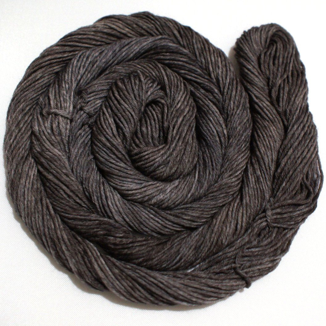 A richly toned swirl of dark brown yarn rests against a clean white background.