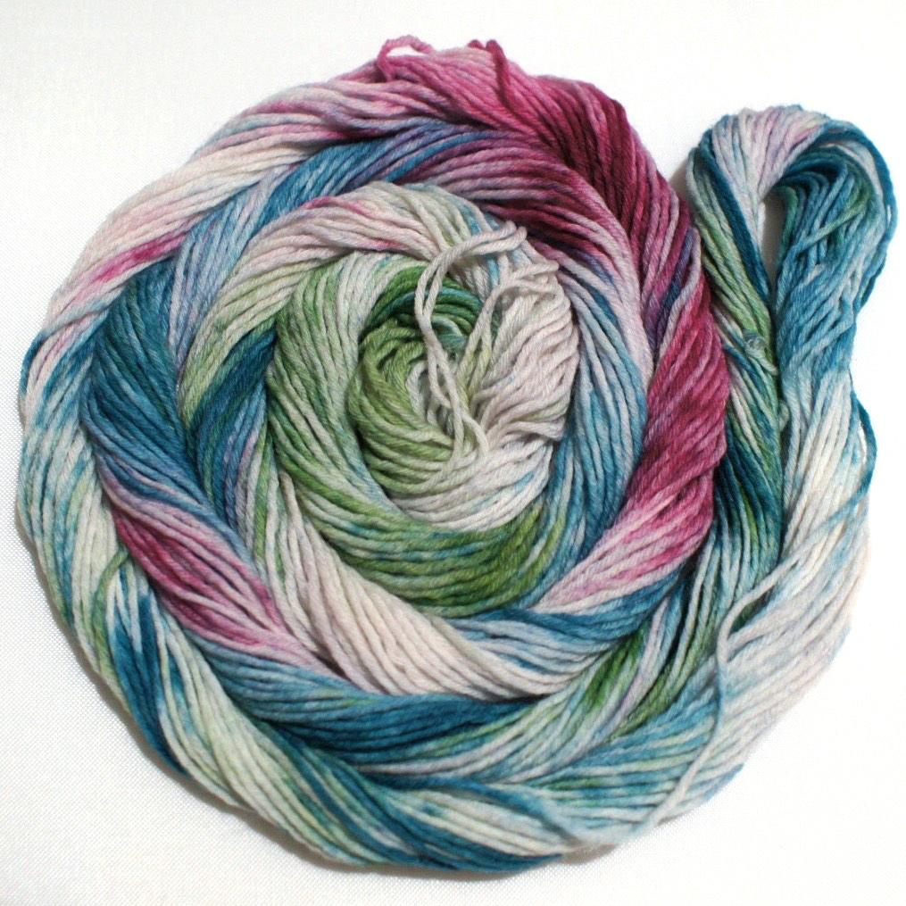 A swirling round of richly colored yarn rests against a clean white background.