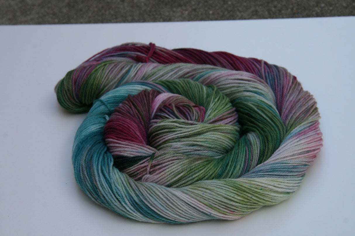 A swirling round of richly colored yarn rests against a clean white background.