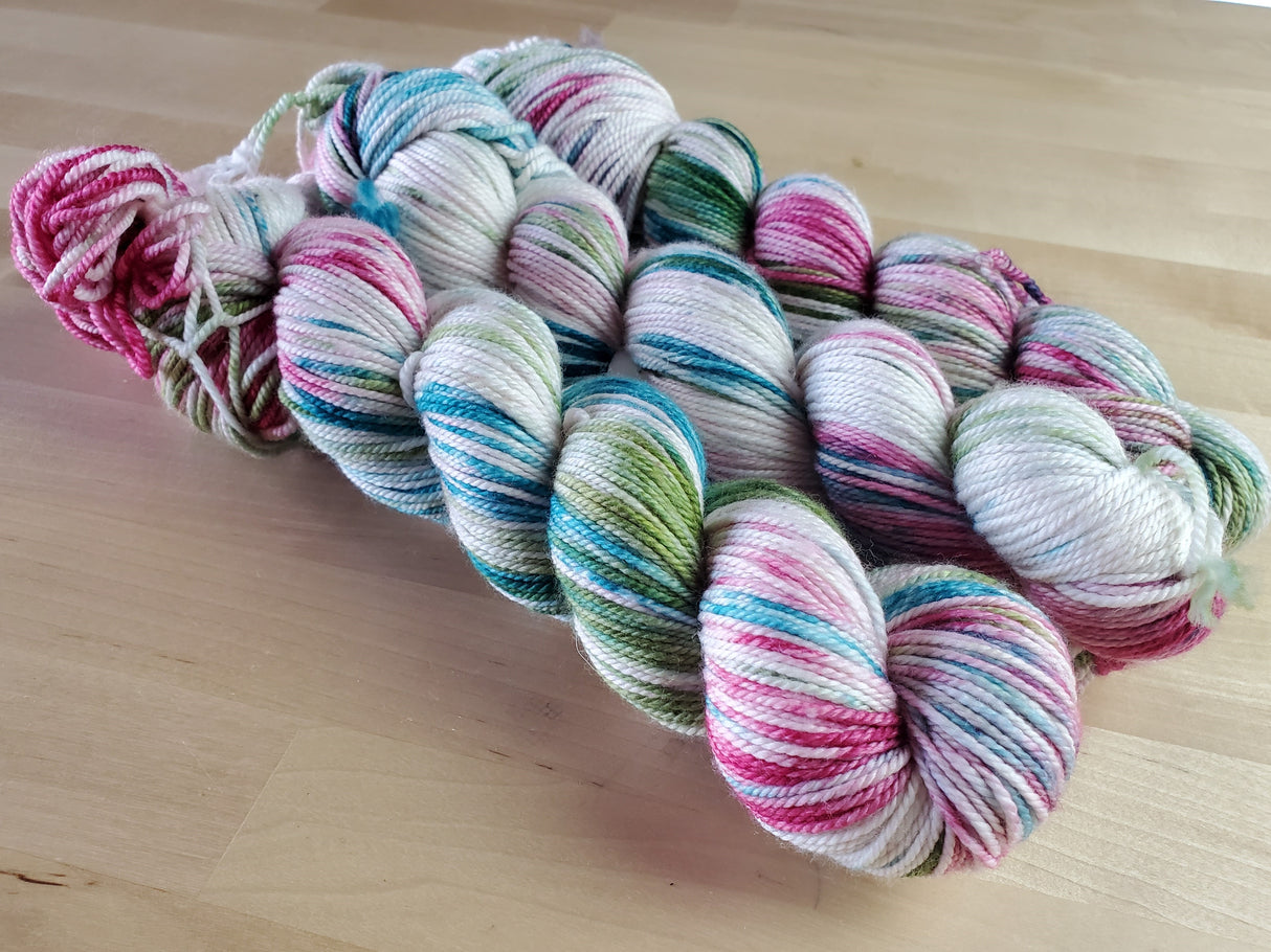 Three skeins of yarn snuggle against a light wooden background.