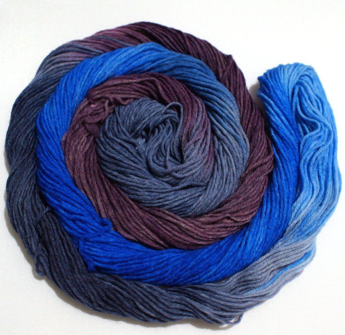 A swirling round of richly colored yarn rests against a clean white background.