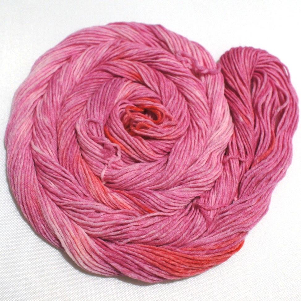A bright swirl of yarn curls around itself like a labyrinth against a white background.
