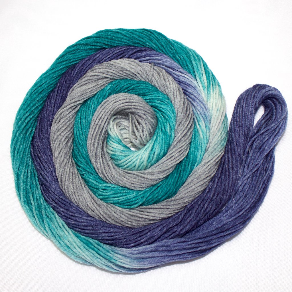 A bright swirl of yarn curls around its self like a labyrinth against a white background.