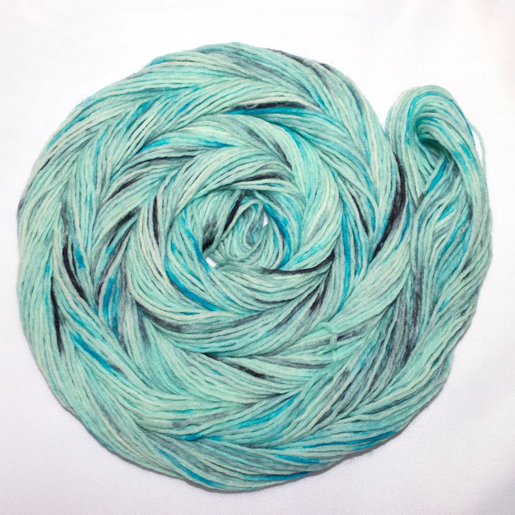 A bright swirl of yarn curls around itself like a labyrinth against a white background.