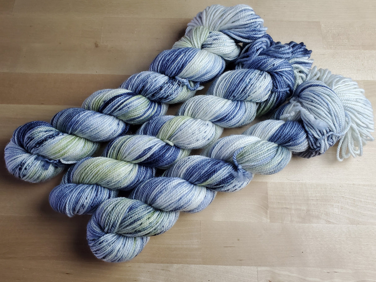 Three skeins of yarn snuggle against a light wooden background.