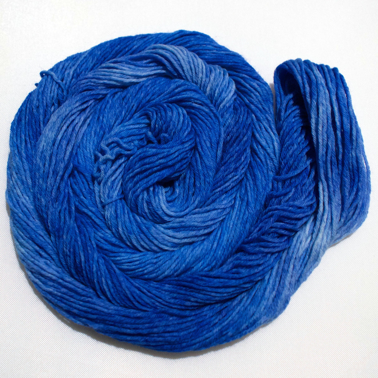 A bright swirl of yarn curls around itself like a labyrinth against a white background.
