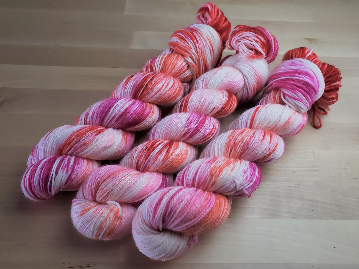 Three skeins of yarn snuggle against a light wooden background.