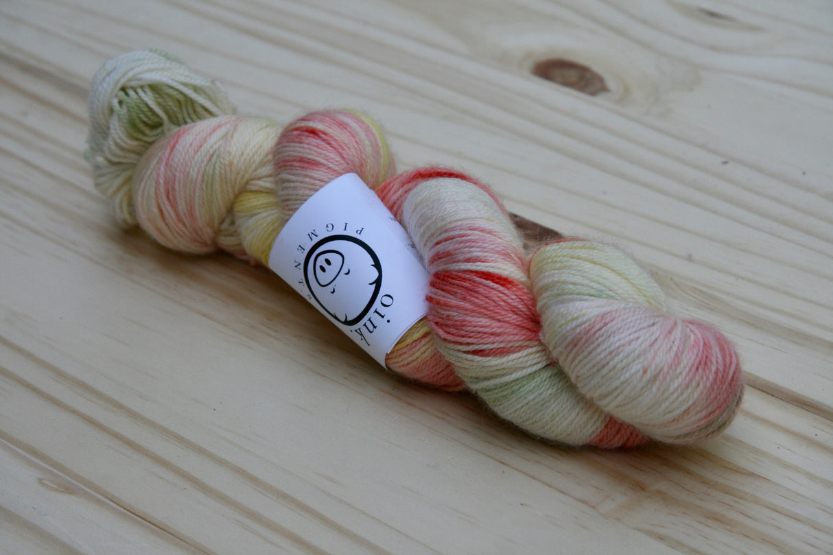 A single twist of yarn rests on a light wooden background.