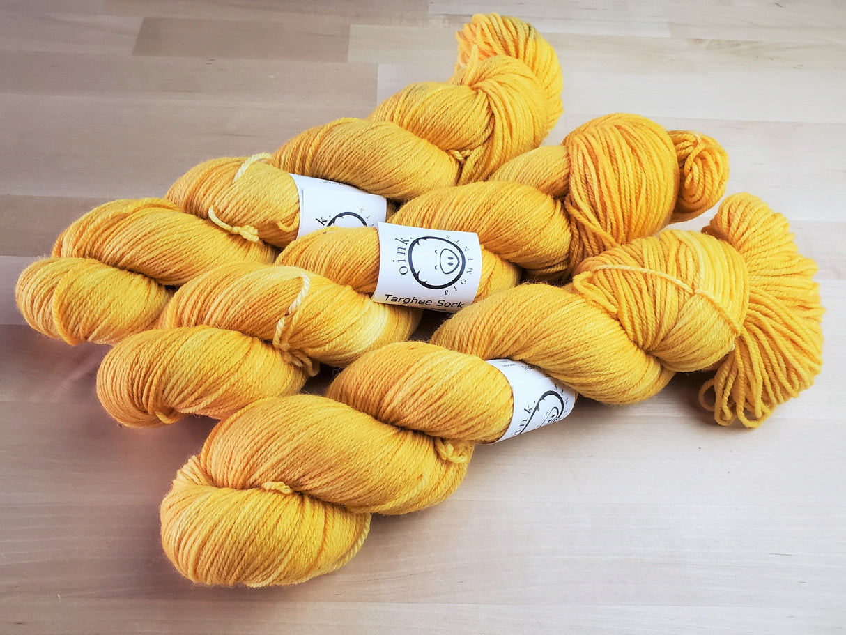 Three skeins of yarn snuggle against a light wooden background.