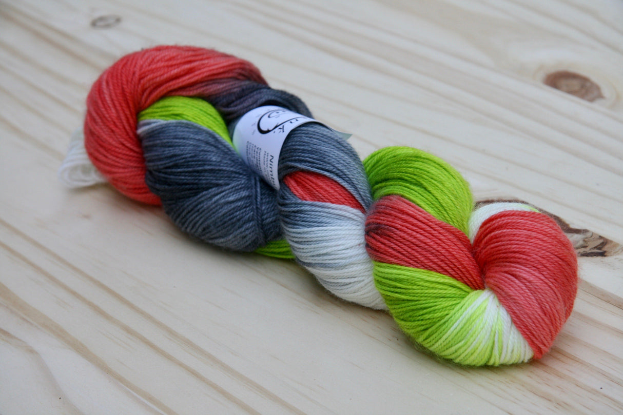 A single twist of yarn rests on a light wooden background.