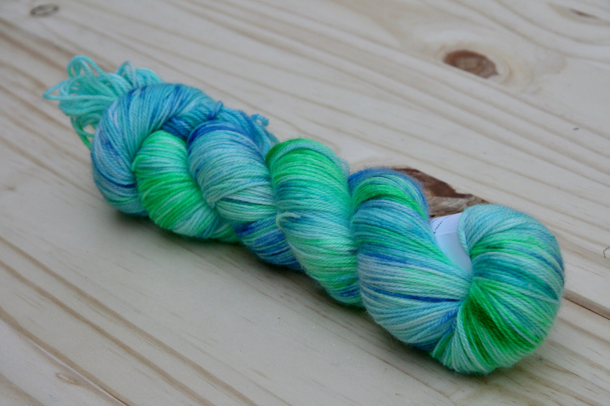 A single twisted skein of yarn rests on a wooden background.