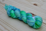 A single twisted skein of yarn rests on a wooden background. 