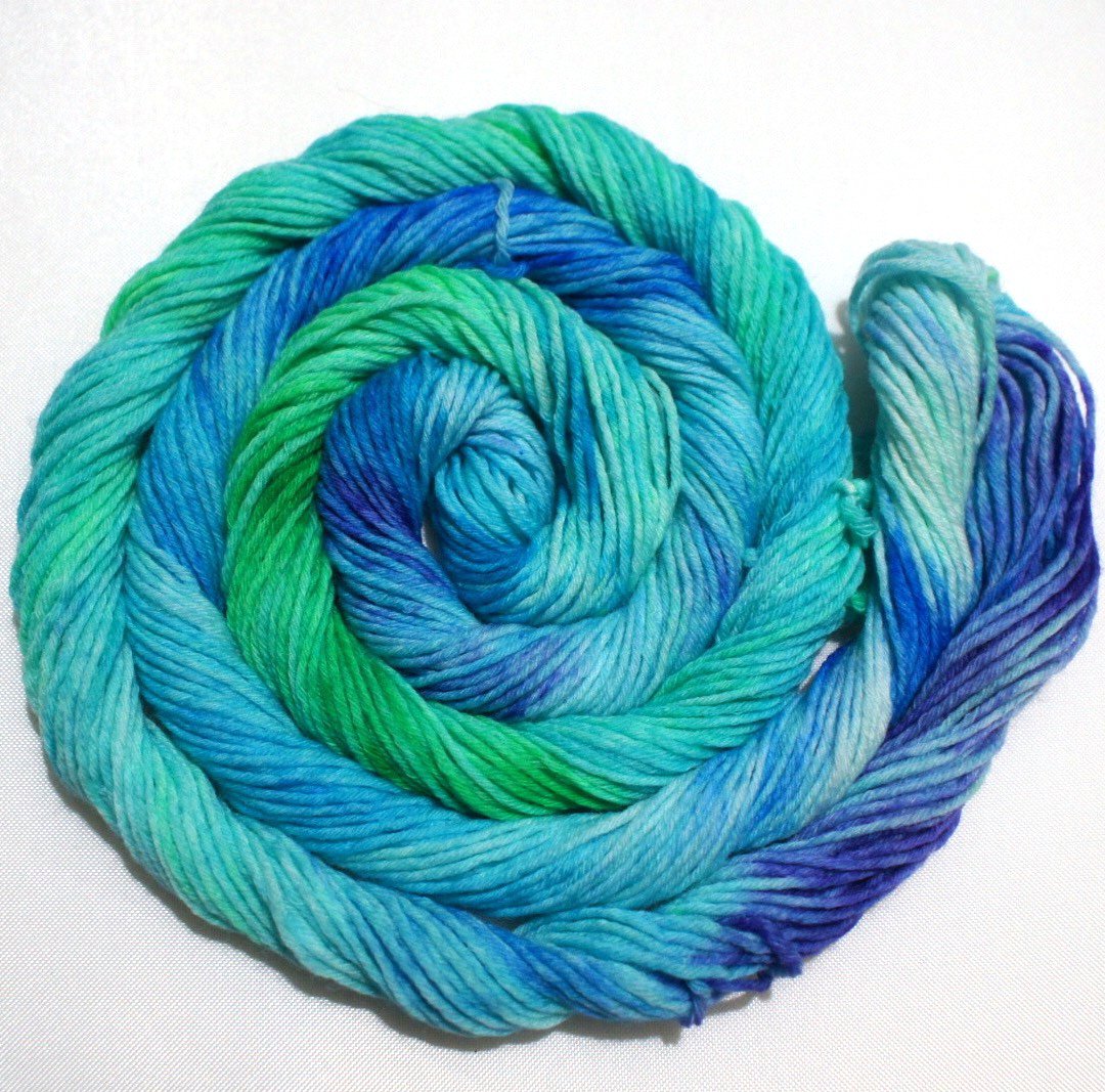 A bright swirl of yarn curls around its self like a labyrinth against a white background.
