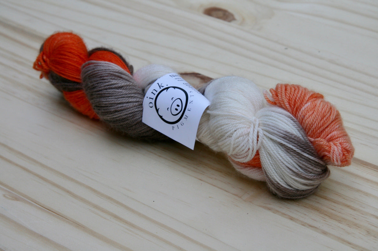 A single twist of yarn rests on a wooden background.