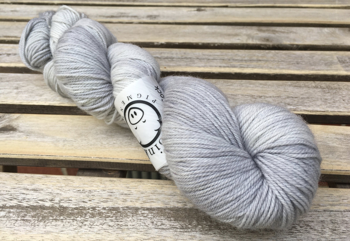 A single twist of yarn rests on a wooden background.