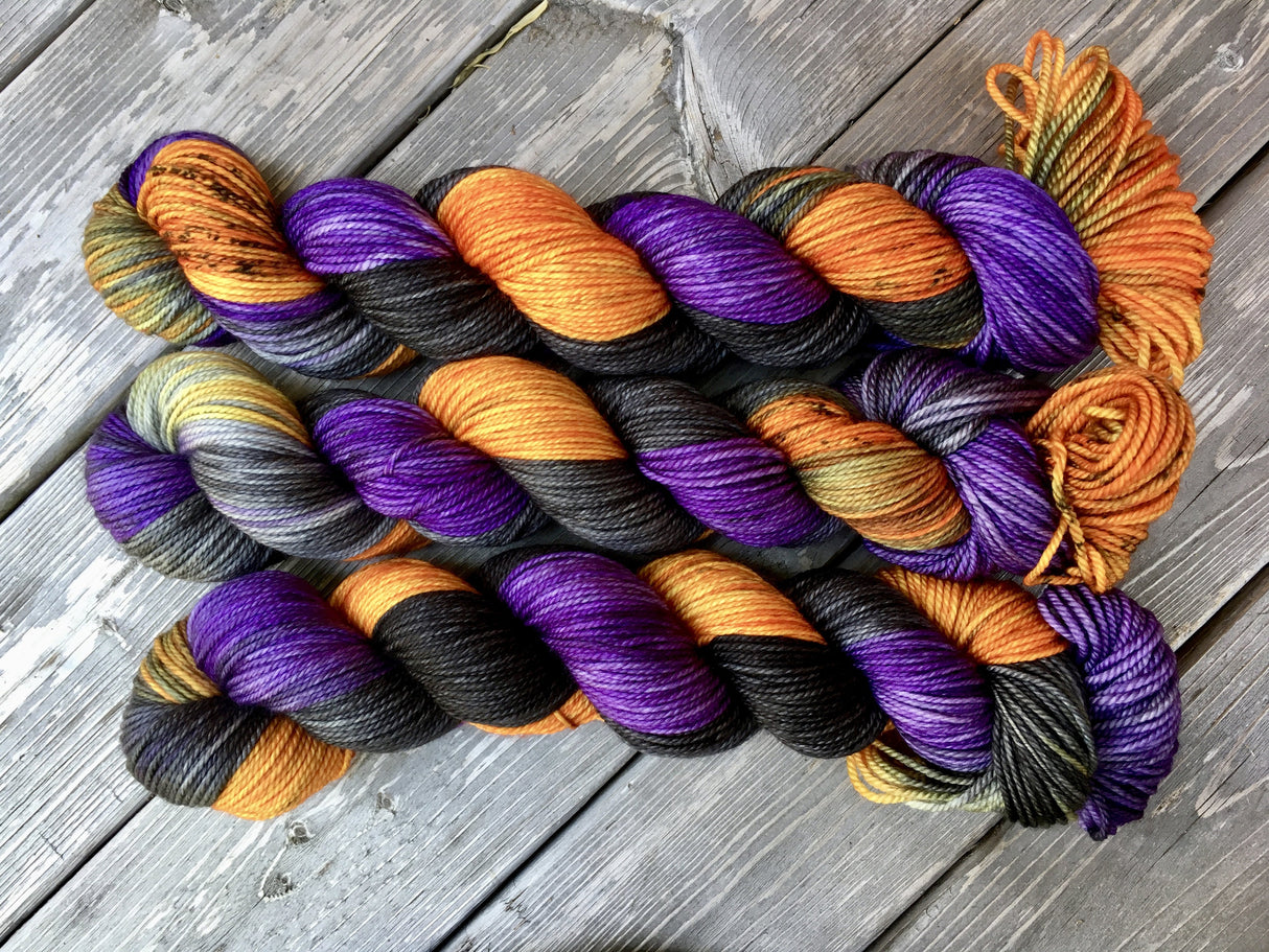 Three skeins of yarn snuggle against a light wooden background.