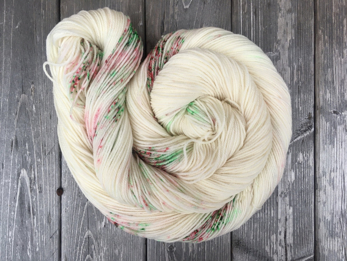 An unfurled skein that looks like a snail with it's shell, rests on a dark wooden background.