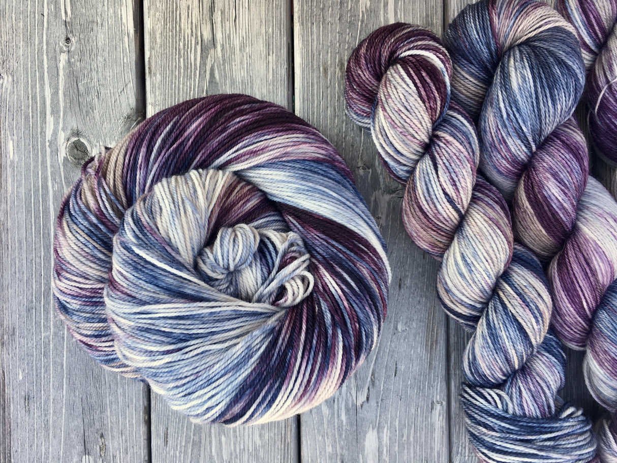 A rich swirl of yarn curls in a cake to the left of the frame, while three twisted skeins peek out from the right.