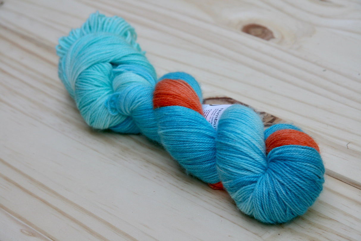 a single twist of yarn rests on a pale wooden background.