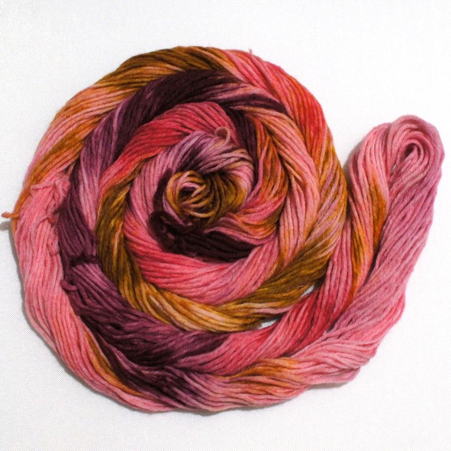 A bright swirl of yarn curls around itself like a labyrinth against a white background.