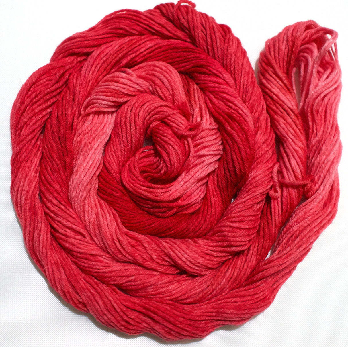 A rich swirl of yarn curls on a clean white background.