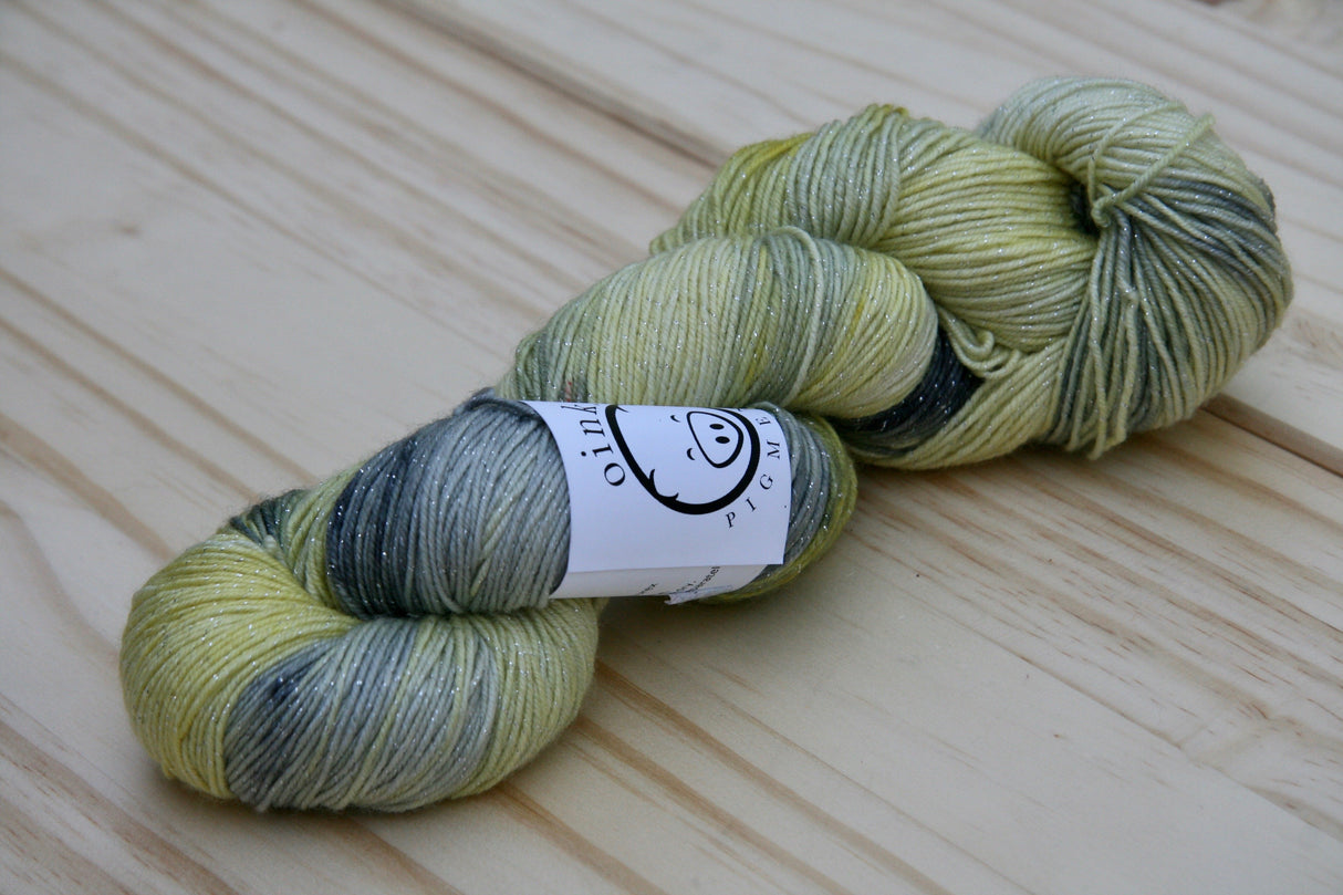 A single twist of yarn rests on a wooden background.