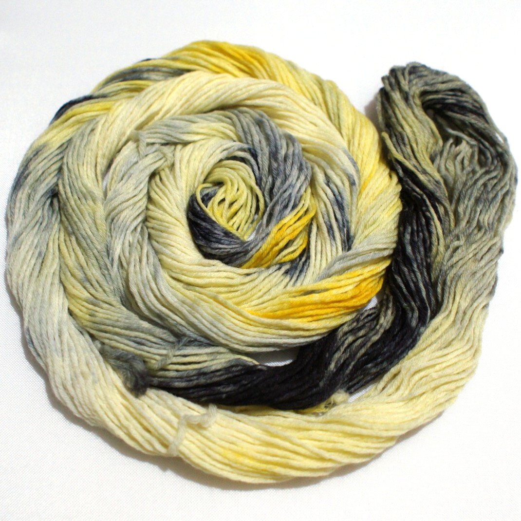 A swirling round of lemon yellow and inky black yarn rests against a clean white background.