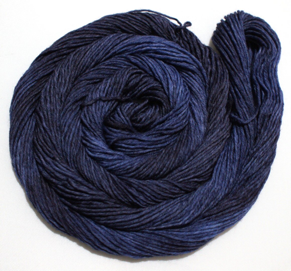 A rich swirl of yarn curls around itself like a labyrinth against a crisp white background.