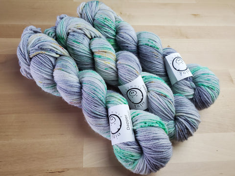 Three skeins snuggle together on a light wooden background.