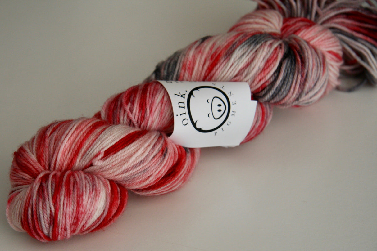 a bright red twist of yarn rests on a white background.