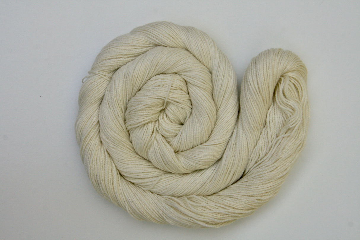 A swirl of pale cream yarn rests on a clean white background.
