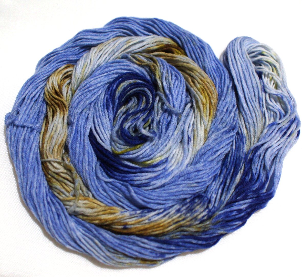 A swirling round of richly colored yarn rests against a clean white background.