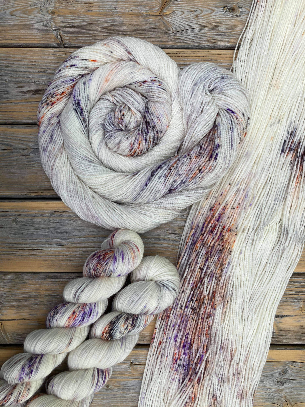 A panoply of yarn in various states of twisting rest on a wooden tabletop.
