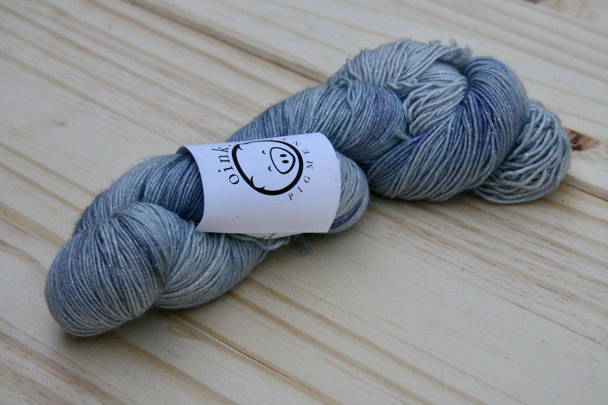 A single twist of yarn rests on a wooden background.