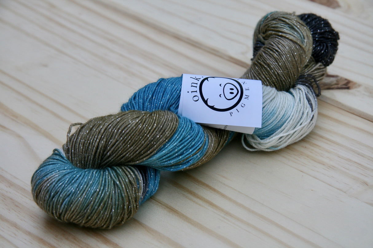 A single twist of yarn rests on a wooden background.