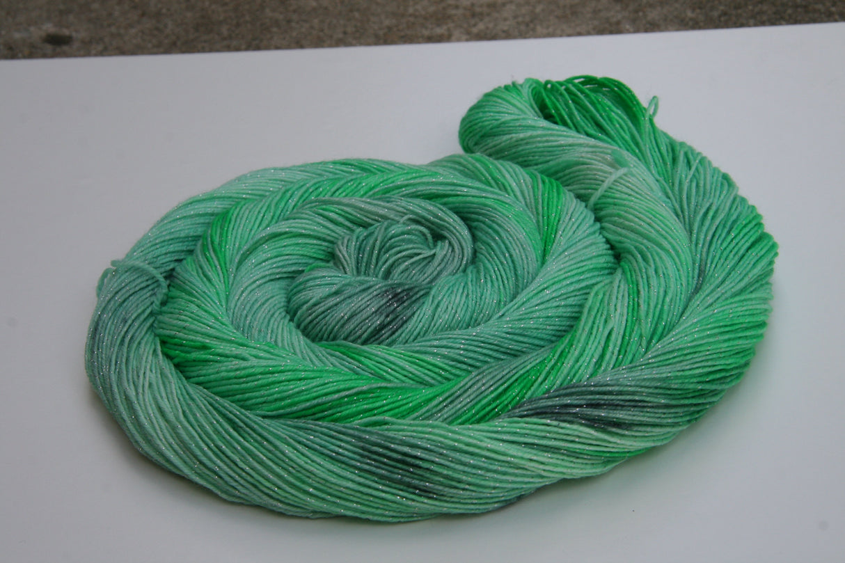 A bright swirl of yarn curls around itself like a labyrinth against a white background.